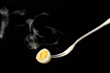 Koyu arkaplanda haşlanmış yumurta ile çatal.