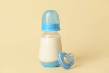 Bebek için bir şişe süt ve arka planda emzik