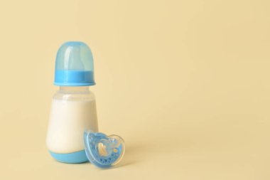 Bebek için bir şişe süt ve arka planda emzik