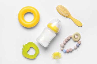 Bebek için bir şişe süt ve beyaz arka planda aksesuarlar.