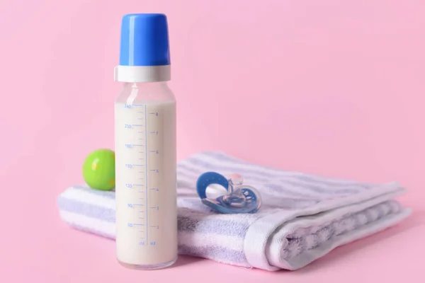 Bottle of milk for baby and accessories on color background