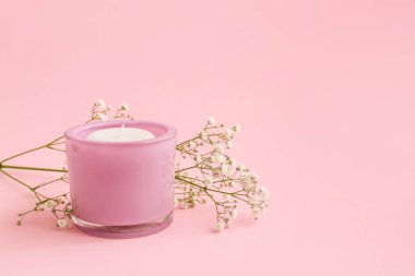 Tutucudaki mum ve renk arkaplanındaki çiçekler