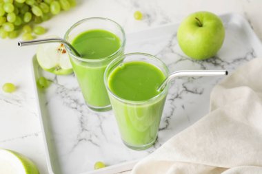 Sağlıklı yeşil smoothie bardakları ve hafif arka planda malzemeler