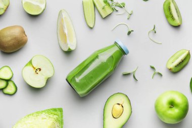 Sağlıklı yeşil smoothie şişesiyle kompozisyon ve hafif arka planda malzemeler