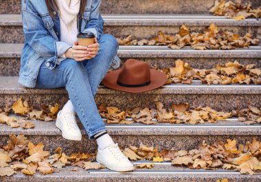 Dışarıdaki merdivenlerde oturan nefis lattesi olan bir kadın.