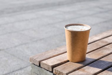 Dışarıdaki bankta bir fincan lezzetli latte, yakın plan.