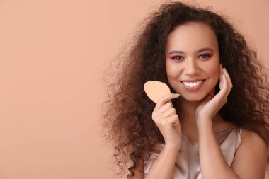 Renkli makyaj süngeri olan güzel bir Afro-Amerikalı kadın.