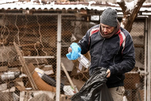 Poor homeless man with trash bag outdoors on winter day