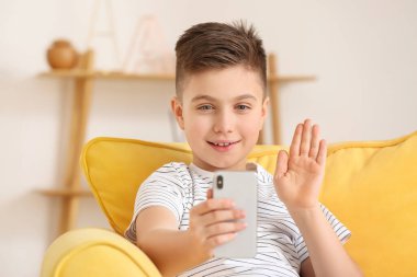 Evde cep telefonu kullanan küçük mutlu çocuk.