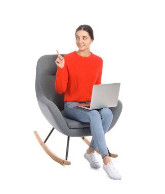 Dizüstü bilgisayarı beyaz arka planda koltukta oturan güzel genç bir kadın.