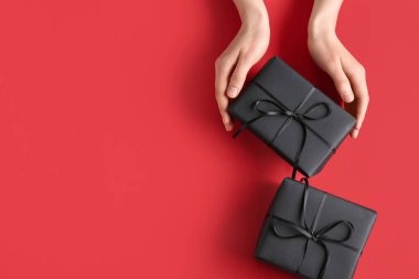 Renk arkaplanında siyah hediye kutuları olan eller