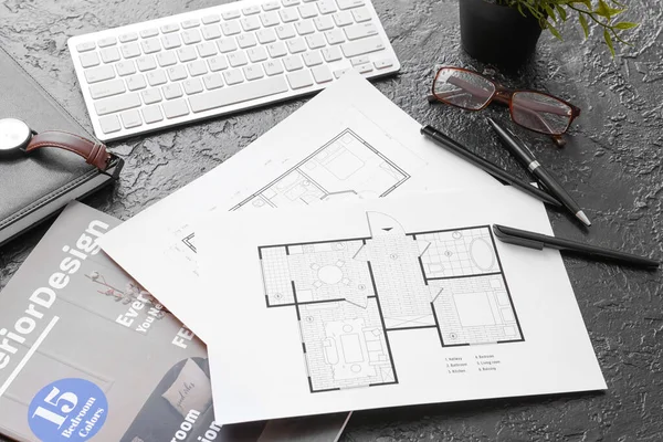 House plans, magazine and computer keyboard on dark background