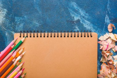 Renk arkaplanındaki defter, kalem ve talaşlar