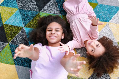 Güzel Afro-Amerikan kız kardeşler halının üzerinde yatıyorlar.