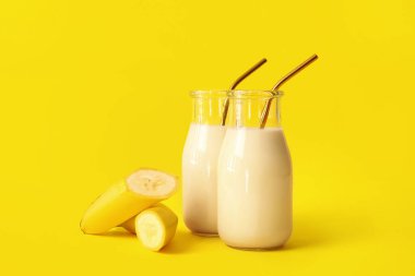 Renkli arkaplanda lezzetli muzlu milkshake şişeleri