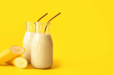 Renkli arkaplanda lezzetli muzlu milkshake şişeleri