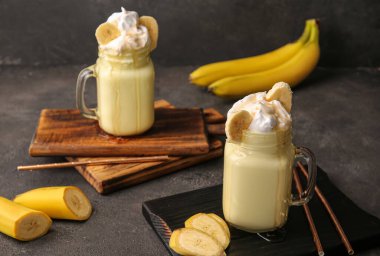 Mason kavanozları koyu arkaplanda muzlu milkshake.