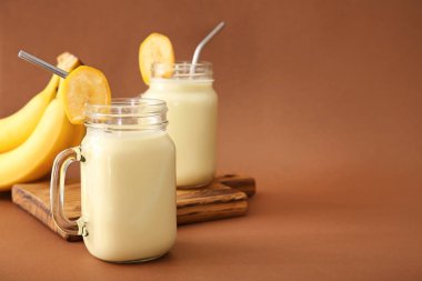 Renkli arkaplanda lezzetli muzlu milkshake kavanozları