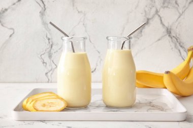 Hafif arkaplanda lezzetli muzlu milkshake şişeleri