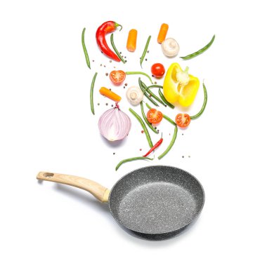 Kızartma tavası ve beyaz arka planda farklı sebzelerle kompozisyon