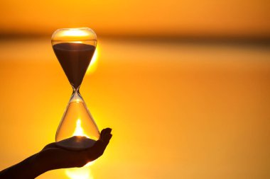 Gün batımında nehrin yanında şık kum saati olan bir kadın.