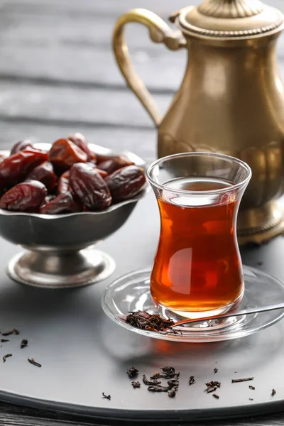 Glass of tasty Turkish tea and dates on dark background