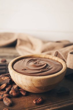 Ahşap arka planda bir kase lezzetli erimiş çikolata.