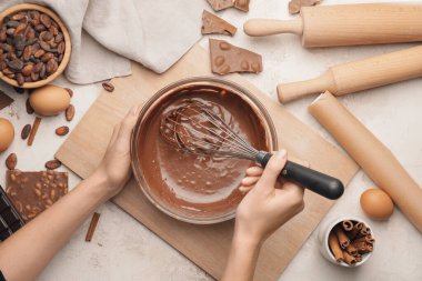 Kadın mutfaktaki masada erimiş çikolata pişiriyor.