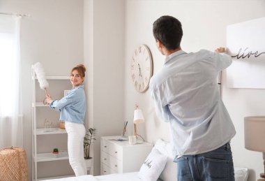 Genç çift yatak odalarını temizliyor.