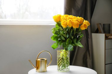 Odanın içindeki masanın üzerinde güzel sarı güller olan vazo.