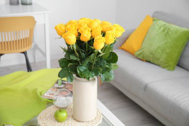 Odanın içindeki masanın üzerinde güzel sarı güller olan vazo.