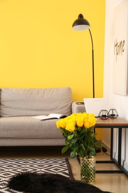 Odanın içinde güzel sarı güller olan vazo.