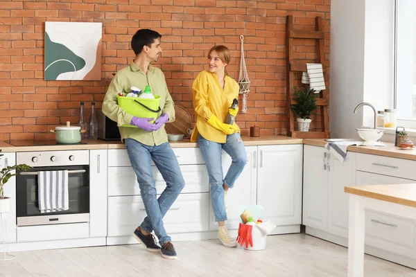 Couple with cleaning supplies in kitchen