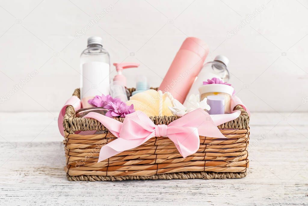 Gift basket with cosmetics on light wooden background
