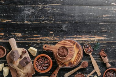 Kakao tozu, fasulye, çikolata ve tereyağı ile koyu ahşap zemin