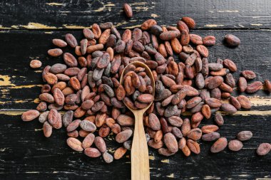 Koyu ahşap arka planda kakao fasulyeli kaşık.