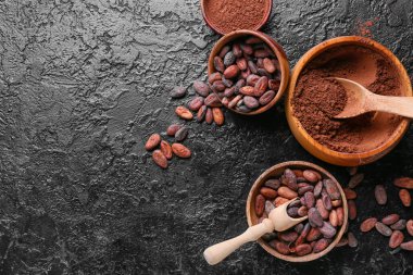 Kakao tozlu kaseler ve koyu arkaplanda fasulyeler.