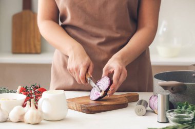 Mutfaktaki masada soğan doğrayan kadın.