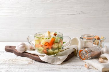 Beyaz ahşap arka planda lezzetli sarımsaklı çorba kasesi.