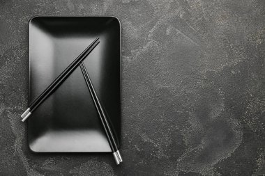 Koyu arkaplanda Çin yemek çubukları olan bir tabak.