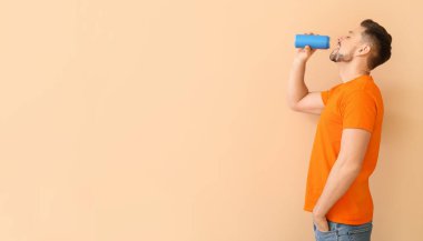 Yakışıklı adam arka planda soda içiyor.