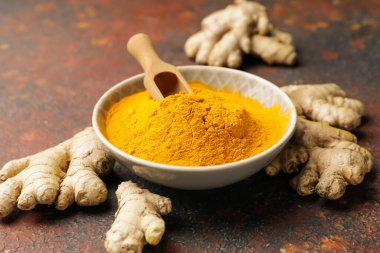 Grunge arka planında zerdeçal tozu ile kase ve kepçe