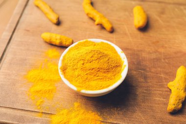 İçinde zerdeçal tozu ve kökleri olan bir kase, yakın plan.