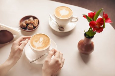 Kafedeki masada bir fincan latte içen kadın.