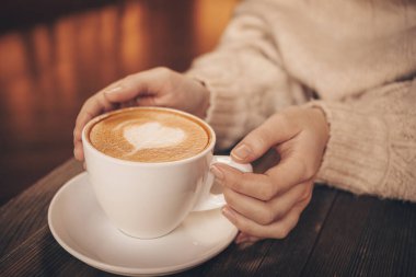 Kafedeki masada bir fincan latte içen kadın.