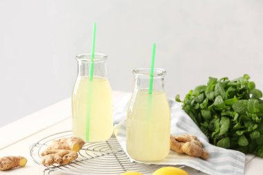 Hafif arkaplanda sağlıklı zencefil suyu şişeleri olan tepsi