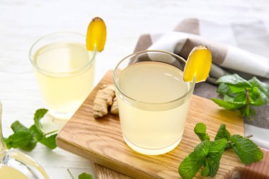 Açık arkaplanda bir bardak sağlıklı zencefil suyu olan bir tahta.