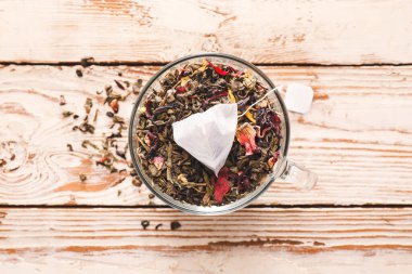 Çay poşeti ve açık ahşap arka planda kuru yapraklar.