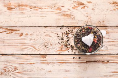 Çay poşeti ve açık ahşap arka planda kuru yapraklar.