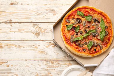 Hafif ahşap zemin üzerinde lezzetli pizzalar olan karton kutu.